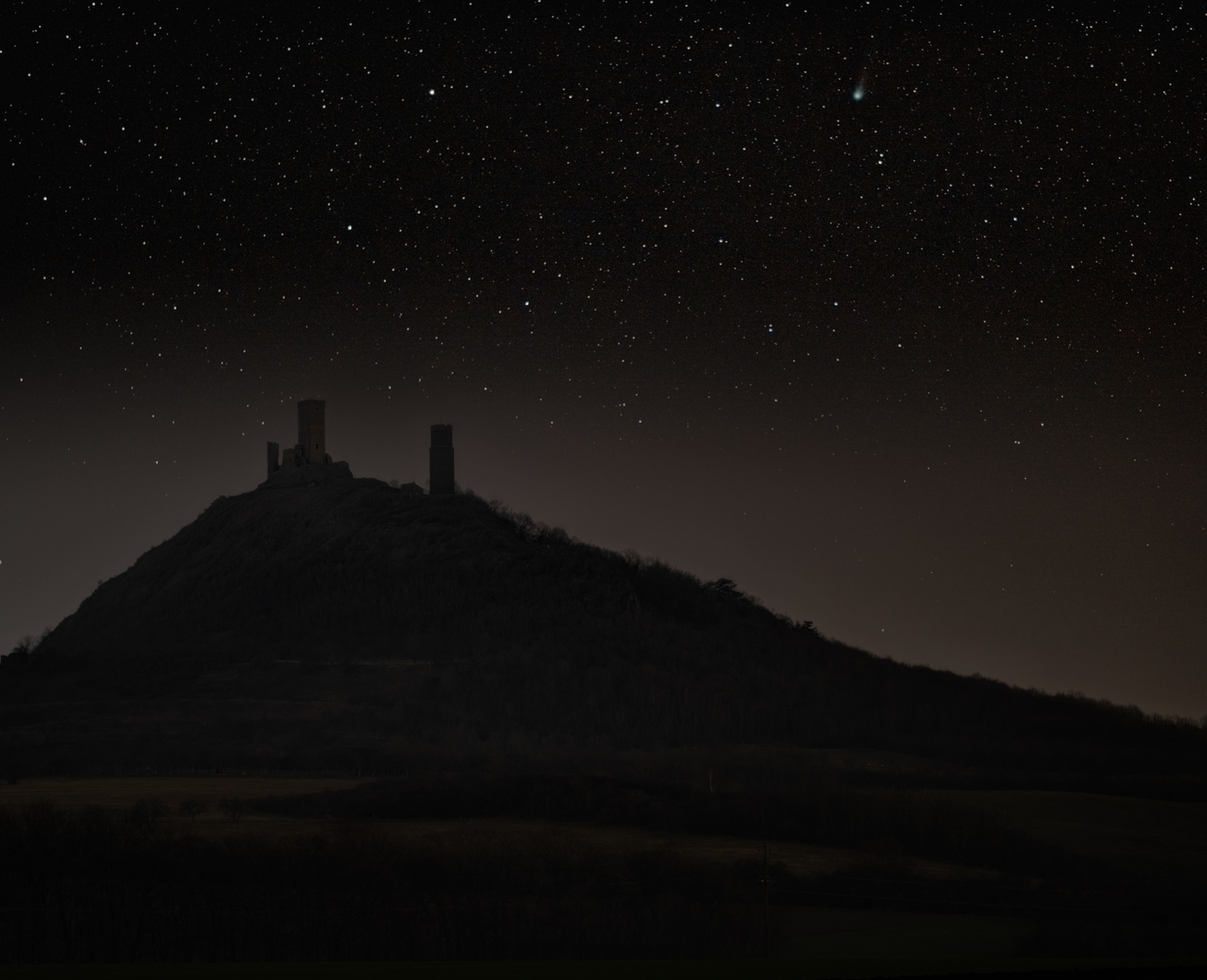 Hazmburk castle at night with stars and 12P/Pons–Brooks
      comet